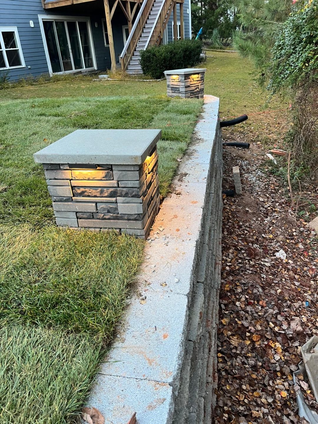Stone-veneer column caps with integrated lighting on a retaining wall