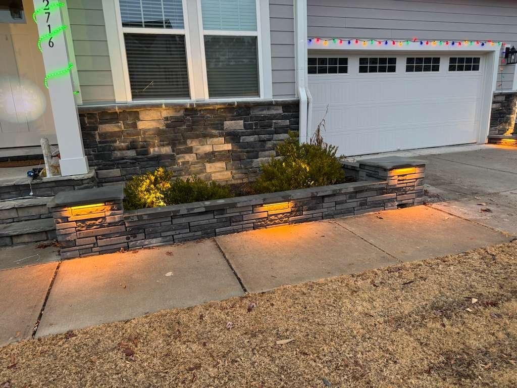Stone veneer retaining wall with landscape lighting